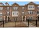 Brick front exterior of townhome with a black metal fence and landscaping at 2065 Morrison Ave, Brookhaven, GA 30319