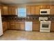 Kitchen with wood cabinets, tile floors, and white appliances at 2250 Rosewood Mill Ct, Loganville, GA 30052