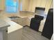 L-shaped kitchen with white cabinets, black appliances, and gray flooring at 230 Valley Xing, Canton, GA 30114