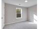 Well-lit bedroom featuring gray walls, carpet, and a window with natural light at 803 Trestle Creek Ct, Temple, GA 30179