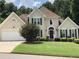 Two-story house with tan siding, brown roof, and landscaping at 310 Medridge Dr, Johns Creek, GA 30022