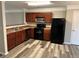 Kitchen with dark wood cabinets, black appliances, and laminate flooring at 837 Crestwell Sw Cir, Atlanta, GA 30331