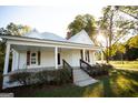 White farmhouse with a front porch, landscaping, and large yard at 10 Maranatha Rd, Mcdonough, GA 30252