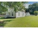 Side view of a white farmhouse with a detached building at 27 Smith St, Locust Grove, GA 30248