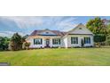 White one-story house with a large front porch, red door and lush green lawn at 1483 Woodlawn Rd, Covington, GA 30014