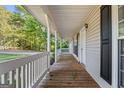 Inviting front porch with wooden flooring and white railing, overlooking a tree-lined street at 125 Laney Ct, Mcdonough, GA 30252