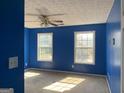 Spacious bedroom with blue walls, two windows, and a ceiling fan at 715 Hennepin Ter, Mcdonough, GA 30253