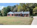 Brick ranch home with a covered porch, well-manicured lawn, and wooded backdrop at 138 Michelle Dr, Mcdonough, GA 30252