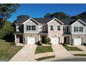 Three-unit townhome building with gray and brick exterior, two-car garages, and landscaping at 142 Hampton Cir, Mcdonough, GA 30253