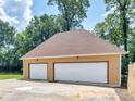Two-car detached garage with white doors and light brown exterior at 32 Peeksville Rd, Locust Grove, GA 30248