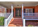 Brick front porch with white railings and black front door at 192 Wynthorpe Way, Douglasville, GA 30134