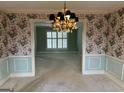 Formal dining room with floral wallpaper, chandelier, and hardwood floors at 4929 Joy Sw Ln, Lilburn, GA 30047