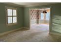 Spacious living room with carpeting, a view into the dining room, and large windows at 4929 Joy Sw Ln, Lilburn, GA 30047