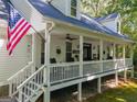 Farmhouse exterior with a wraparound porch and American flag at 313 Dingler Rd, Moreland, GA 30259