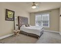 Well-lit bedroom featuring a tufted headboard, window, and carpeted floors at 12795 Wyngate, Alpharetta, GA 30005