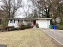 Single-story home with white brick exterior, attached garage, and a driveway leading to the entrance at 2830 Battle Forrest Dr, Decatur, GA 30034