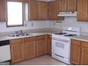 Compact kitchen featuring wooden cabinets, white appliances, and light countertops at 5920 Homestead Ct, Rex, GA 30273