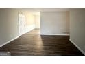 Spacious, empty living room with wood-look flooring, white walls, and a door leading to another room at 1519 Pine Glen Cir, Decatur, GA 30035