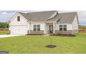 Newly constructed home with white siding, gray roof, and a well-manicured lawn at 940 Hesston Dr, Locust Grove, GA 30248