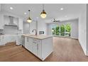 Open concept kitchen features modern white cabinets, island, and hardwood floors at 8212 Main St # 1202, Woodstock, GA 30188