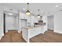 Modern white kitchen with island, hardwood floors, and stainless steel appliances at 8212 Main St # 1202, Woodstock, GA 30188