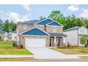 Two-story house with stone and blue siding, a white garage door, and landscaping at 7771 Richmond Trl, Fairburn, GA 30213