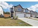 Two-story townhome with stone and white siding, two-car garage, and landscaping at 269 Bald Ave # 18, Stockbridge, GA 30253