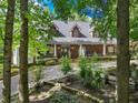 Brick home nestled amongst lush trees, featuring a stone driveway and beautiful landscaping at 3920 Drew Campground Rd, Cumming, GA 30040