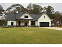 White farmhouse exterior with black accents, large windows, and a spacious lawn at 11 Harmony Ridge Dr, Temple, GA 30179