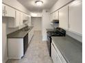 Galley kitchen with white cabinets, gray countertops, and black appliances at 1472 Pine Log Ne Rd, Conyers, GA 30012