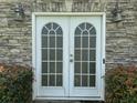 White double French doors leading to the basement, set in a stone wall at 2112 Bradford Pear Se Cir, Conyers, GA 30013