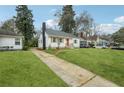 Charming white house with orange door, landscaped lawn, and long driveway at 1875 Langston Sw Ave, Atlanta, GA 30310