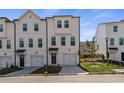 Three-story townhouse with white siding, two-car garage, and front yard at 77 Werner Brook Way, Atlanta, GA 30354