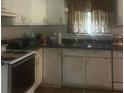 Galley kitchen with white cabinets, stove and double sink at 4356 Housworth Dr, Stonecrest, GA 30038