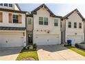 Townhouse with white brick exterior, two-car garage, and landscaping at 228 Auburn Valley Way, Auburn, GA 30011