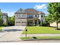 Two-story house with brick facade, three-car garage, and landscaped lawn at 4550 Fernbrook Pl, Cumming, GA 30040