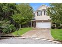 Two-story townhome with a beige exterior, two-car garage, and landscaped yard at 6393 Shadow Sq, Lithonia, GA 30058