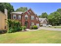 Brick two story house with a large green lawn and driveway at 230 Ridge Bluff Ln, Suwanee, GA 30024