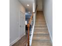 Carpeted staircase with a wooden railing and metal balusters at 6194 Ripple Way # 86, South Fulton, GA 30349