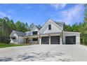 Modern farmhouse exterior with three-car garage and manicured lawn at 321 Roper Rd, Canton, GA 30115