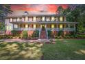 Two-story house with wrap-around porch, brick accents, and well-lit landscaping at 3060 Orchard Sw Rd, Conyers, GA 30094