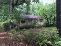 Small house with a front porch, surrounded by overgrown vegetation at 2165 Old Salem Se Rd, Conyers, GA 30013
