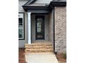 Front entryway featuring a black door, stone steps, and brick exterior at 5544 Whispering Swan Ct, Douglasville, GA 30135