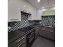 Modern kitchen with dark gray and white cabinets, glass tile backsplash and black countertops at 375 Ralph Mcgill Blvd # 505, Atlanta, GA 30312