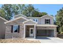 Two-story house with brick and siding exterior, brown door, and white garage door at 7015 Brushwood Bend (Lot 65), Lithonia, GA 30058