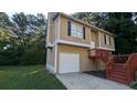 Tan two-story house with red stairs and attached garage at 5300 Forest Downs Ln, Atlanta, GA 30349