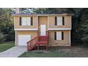 Tan two-story house with red stairs and attached garage at 5300 Forest Downs Ln, Atlanta, GA 30349