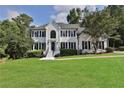 Two-story white brick house with black shutters, a manicured lawn, and mature trees at 3126 Crestmont Nw Way, Kennesaw, GA 30152