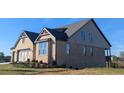 Brick house with a three-car garage and partial view of the backyard at 2235 Windsor Bluffs Dr, Cumming, GA 30041