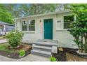 White brick ranch home with teal door, landscaping, and a paved walkway at 408 Belgarde Place Se, Atlanta, GA 30354